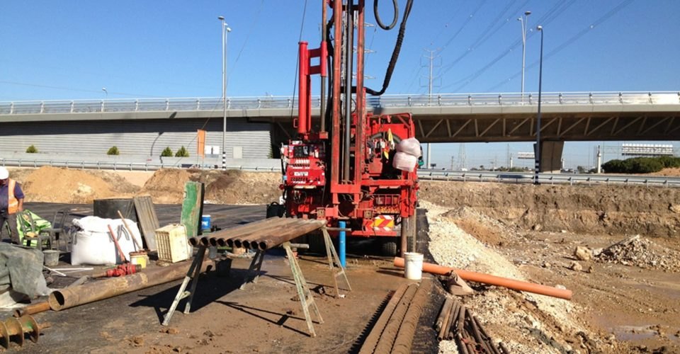 Drill rig carrying out geotechnical investigation beside a bridge